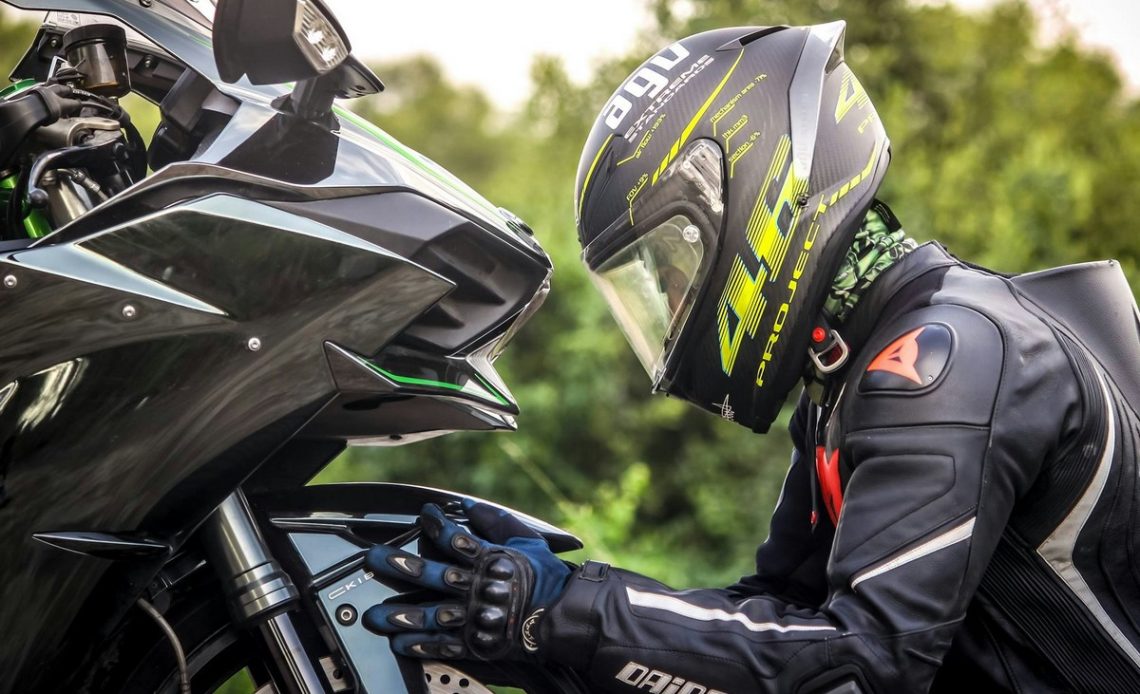 Motocyklista w kasku trzymający oponę